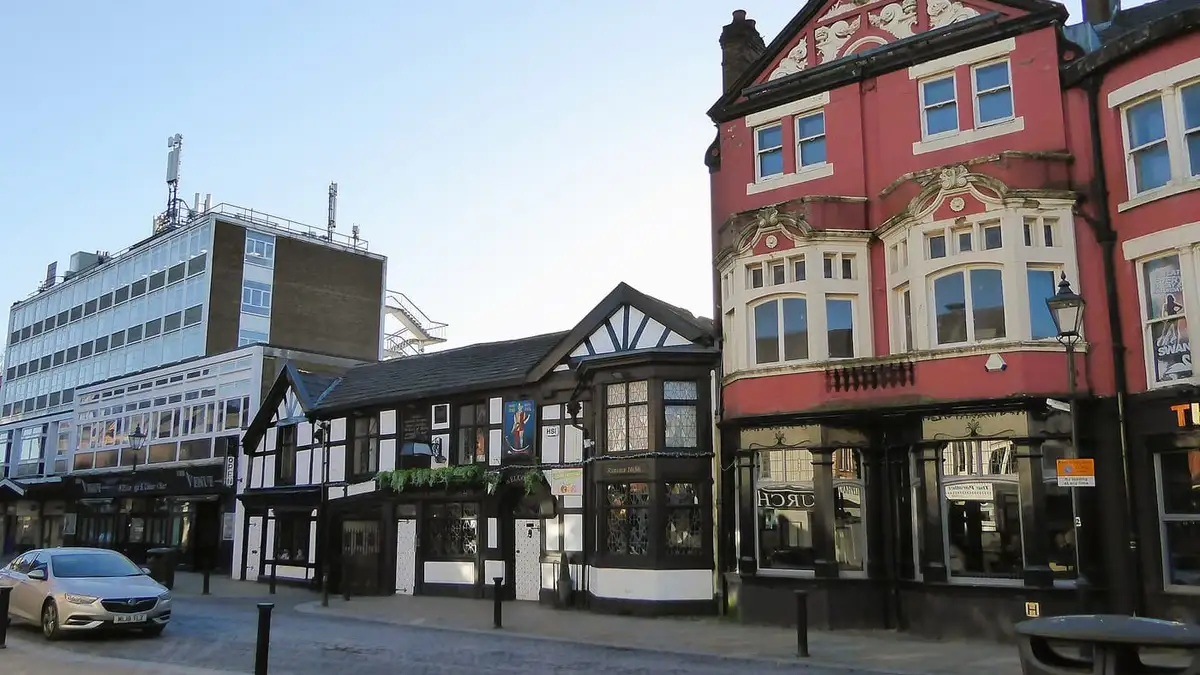 Historic pubs and buildings on cobbled Churchgate, Bolton town centre