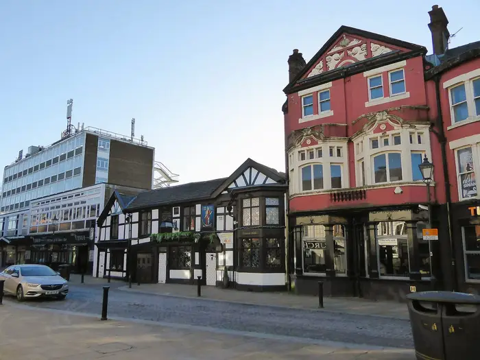 Historic pubs and buildings on cobbled Churchgate, Bolton town centre