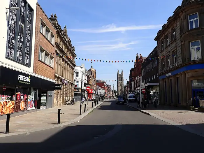 Shops and Victorian buildings along Deansgate, Bolton, under a blue sky
