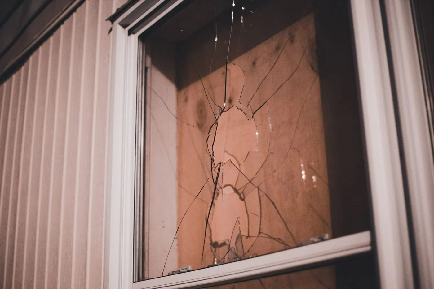 Cracked window pane with spreading fractures, seen at night