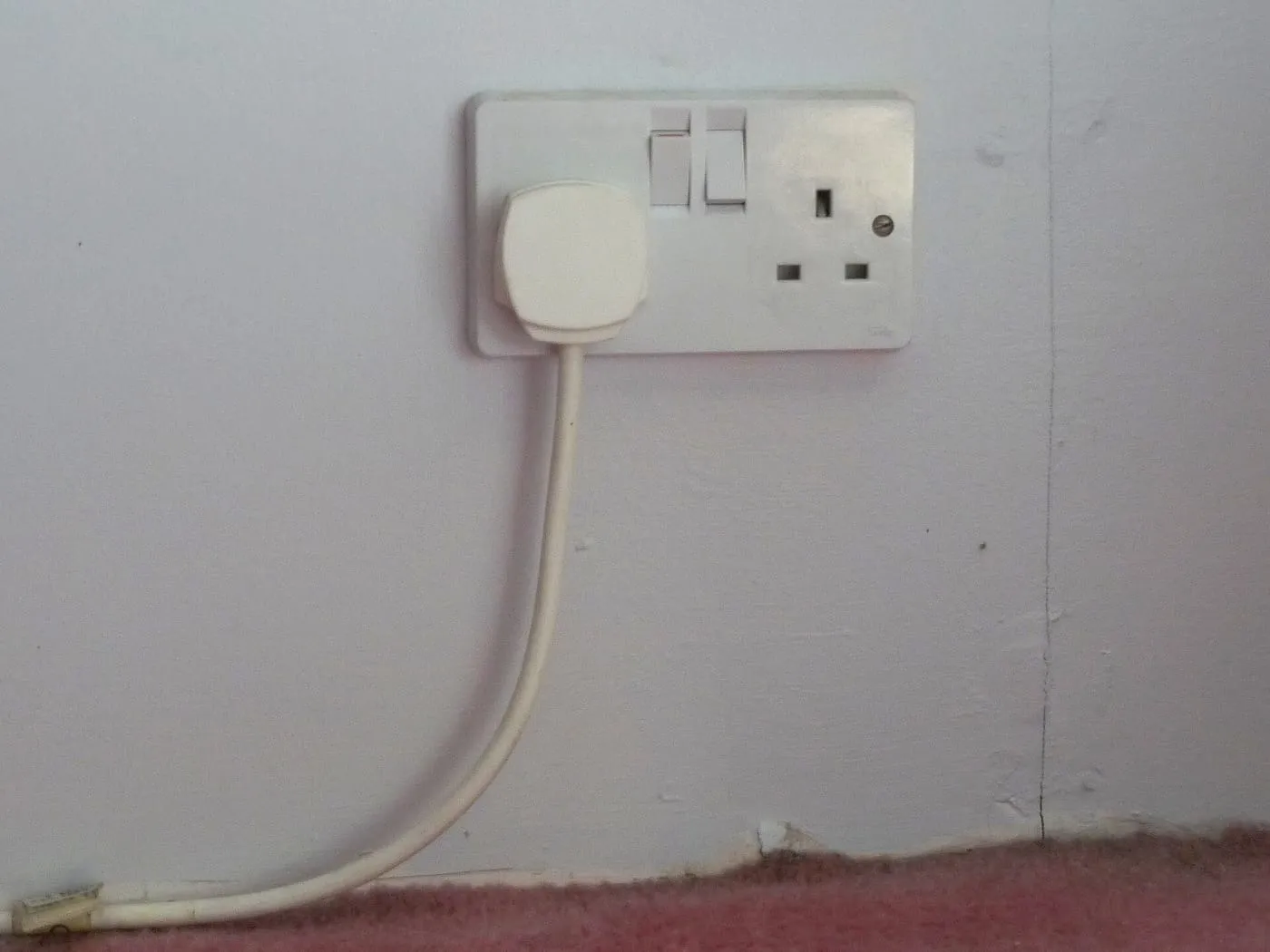 UK double wall socket with a plug switched on in one outlet