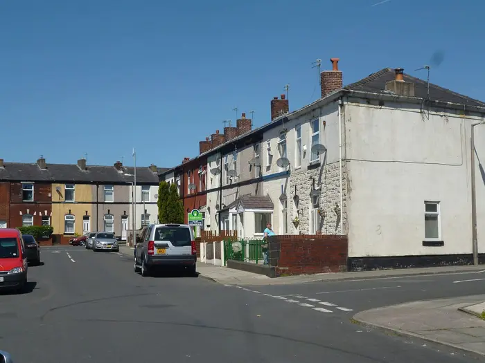 Painted terraced houses on Laurel Street, Bury, under a blue sky
