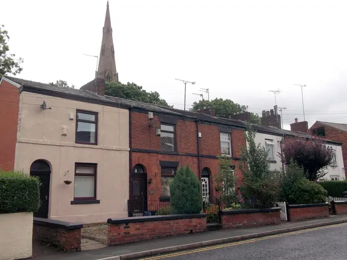 Brick cottages on Pole Lane near Failsworth Pole, with church spire