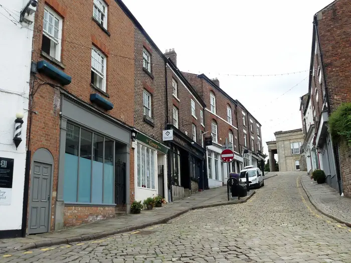 Listed brick shops on cobbled Church Street, Macclesfield town centre
