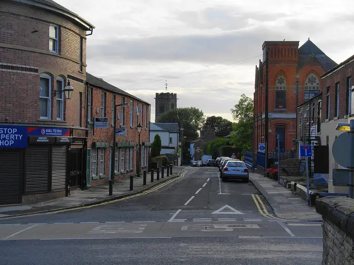 Shops on Church Lane, Prestwich, with St Mary's Church tower beyond