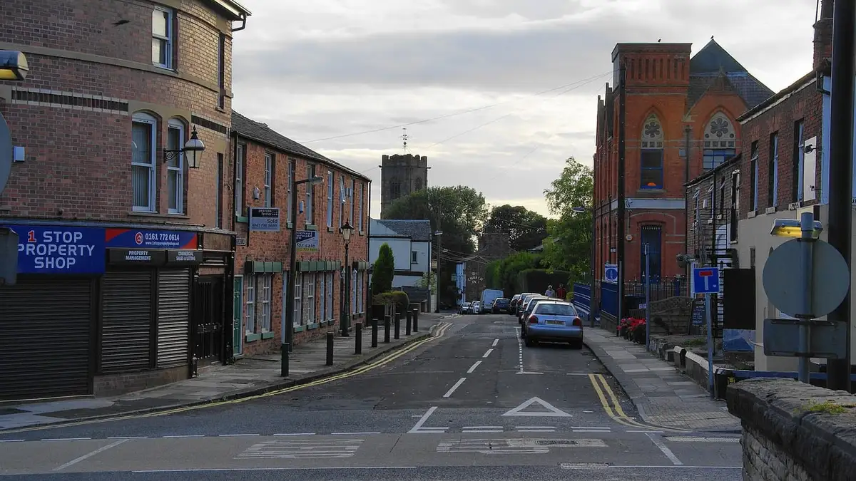 Shops on Church Lane, Prestwich, with St Mary's Church tower beyond