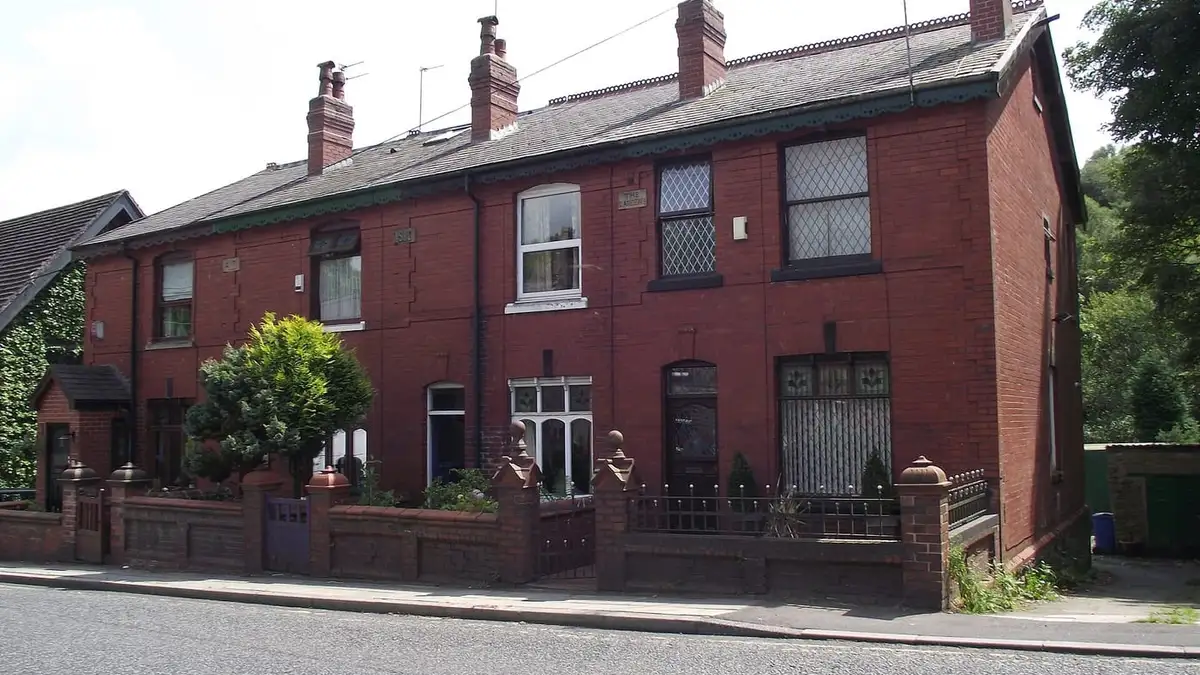 Slate roofs and brick chimneys on red-brick terraced houses in Hawkshaw, Greater Manchester
