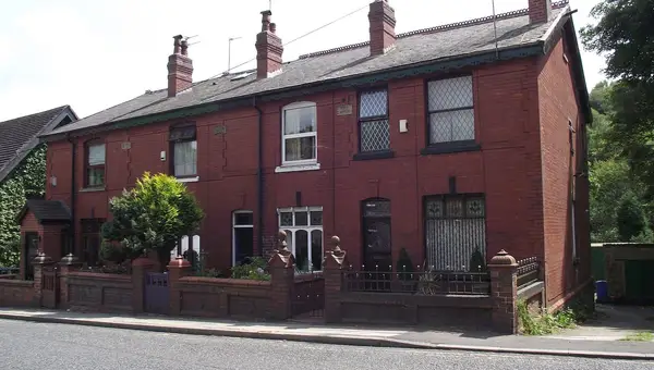 Slate roofs and brick chimneys on red-brick terraced houses in Hawkshaw, Greater Manchester