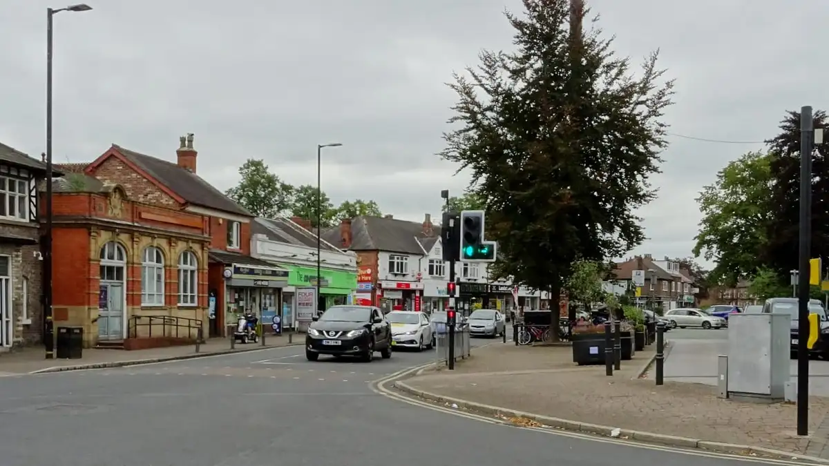 Shops and a red-brick building at a junction in Timperley village centre