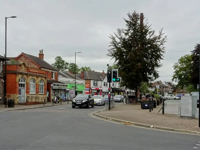 Shops and a red-brick building at a junction in Timperley village centre