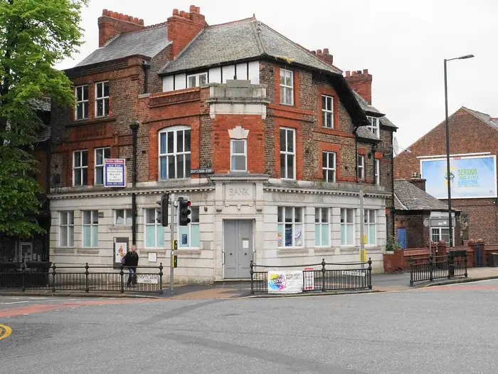 Red-brick former bank building on a corner in Urmston town centre