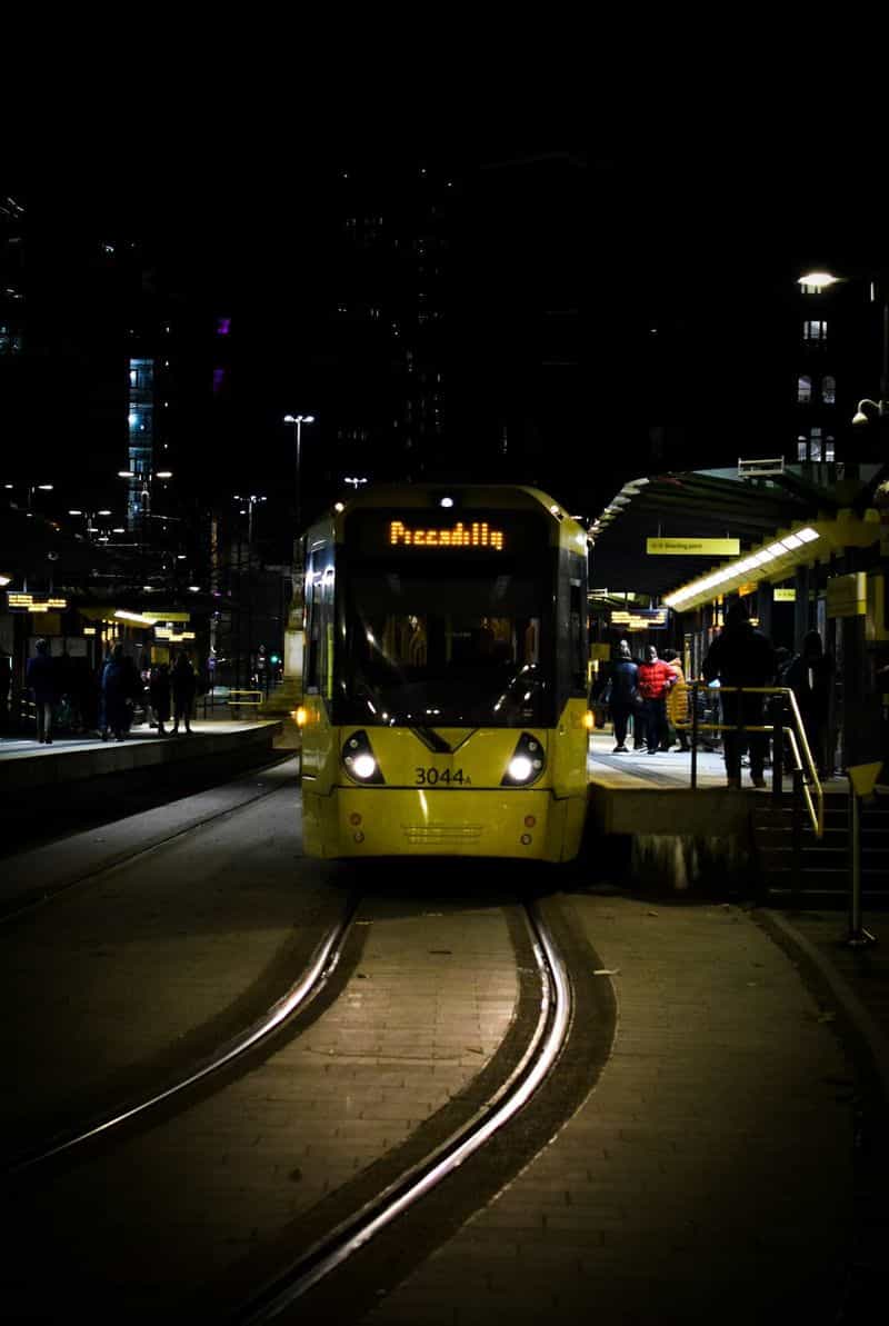 Yellow Manchester tram on a city street at night